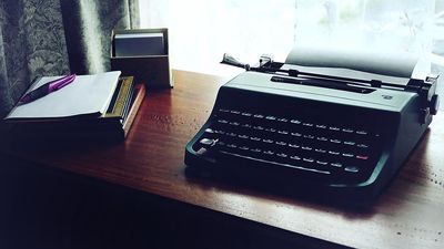 Стол без единого экрана: печатная машинка, блокнот, свет из окна